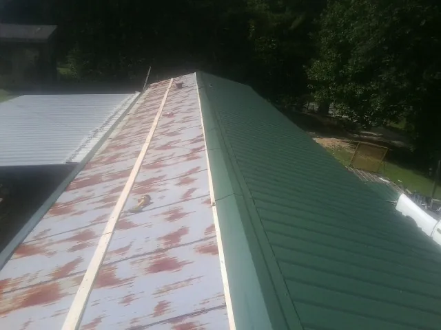 Old rusted panels beside newly installed green metal roofing — Wind Damage Roof Repair by Roofing Brothers in Mckeesport