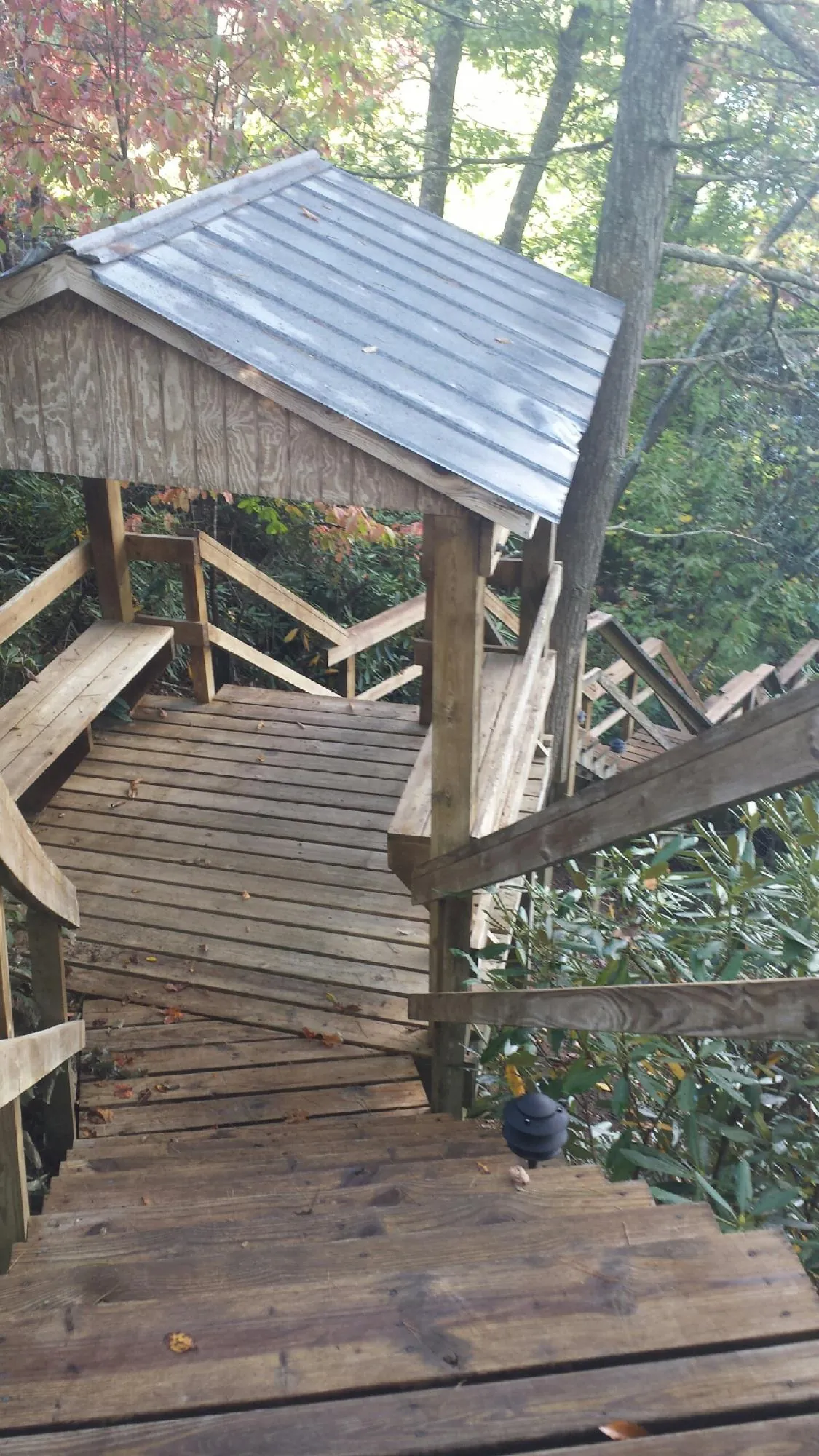 Metal roofed shelter over wooden steps on a wooded walkway — Skylight Repair & Installation work by our crew in Mckeesport