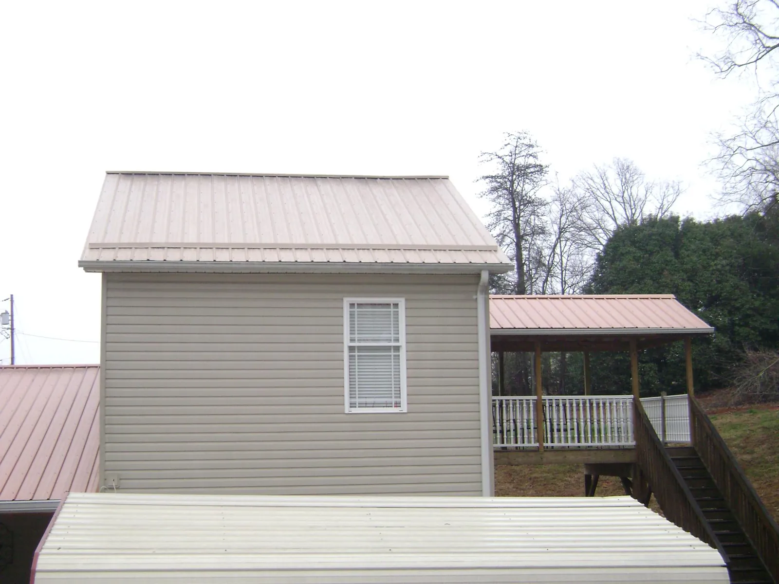 Tan metal roofs on a two story addition and attached porch, from a Roof Replacement job in Mckeesport