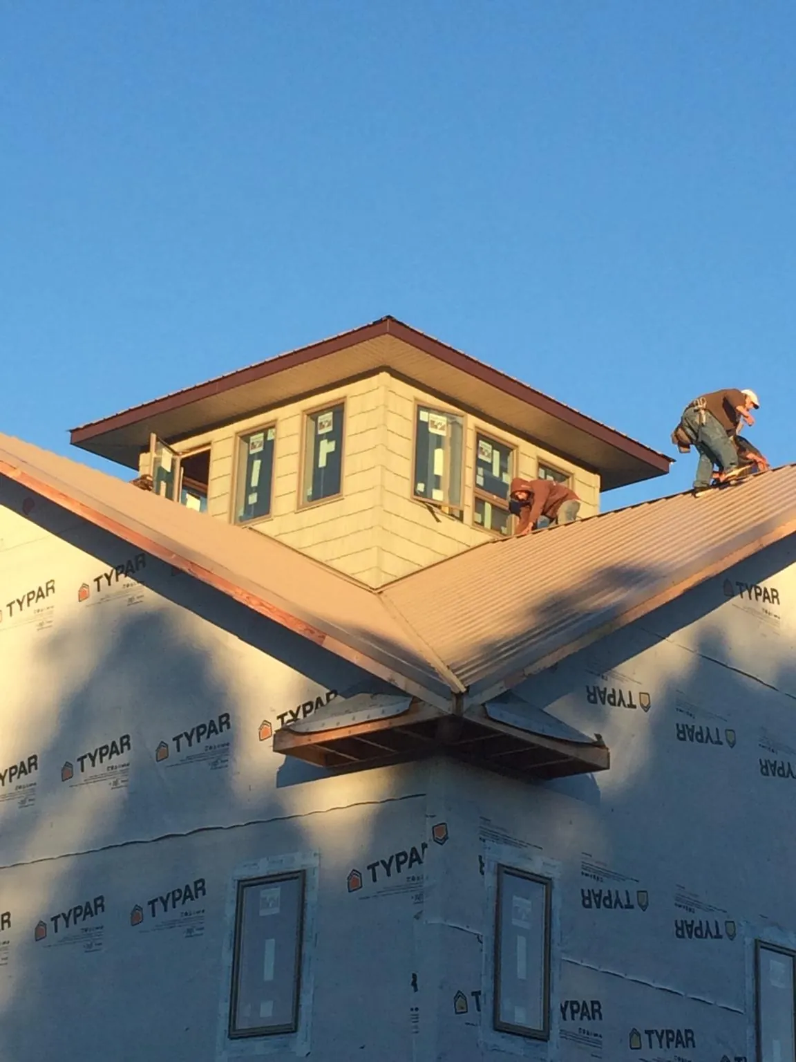 Roofers working around a rooftop cupola on a new metal roof at sunset — Roof Waterproofing in Mckeesport by Roofing Brothers